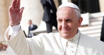 Pope Francis smiles slightly and waves