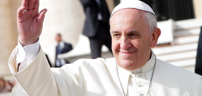 Pope Francis smiles slightly and waves